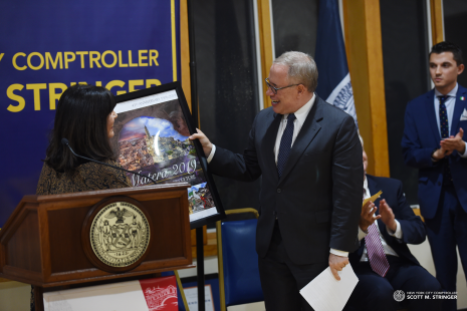 October 2019 - New York City Comptroller Scott Stringer proudly shows the annual theme poster at his Proclamation Ceremony as IHCC-NY, Inc. Board member Cav. Joan Marchi Migliori presents it.